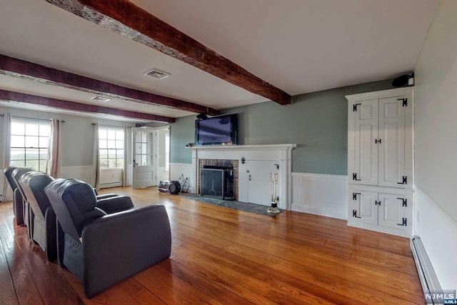 living room with a fireplace, beam ceiling, wood-type flooring, and baseboard heating