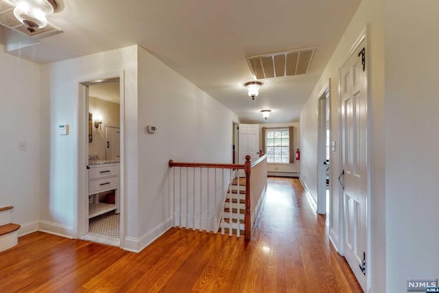 hallway featuring a baseboard heating unit and hardwood / wood-style flooring