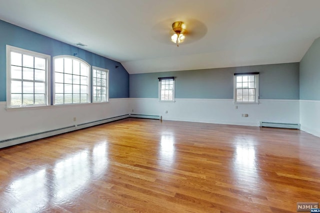 unfurnished room with ceiling fan, light hardwood / wood-style flooring, baseboard heating, and vaulted ceiling