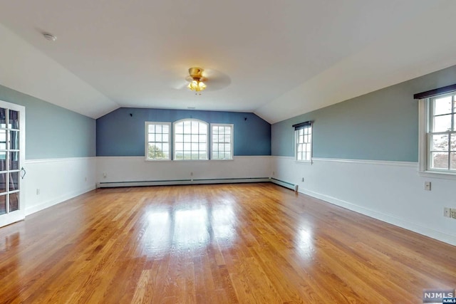 bonus room featuring light wood-type flooring, a baseboard radiator, a wealth of natural light, and lofted ceiling