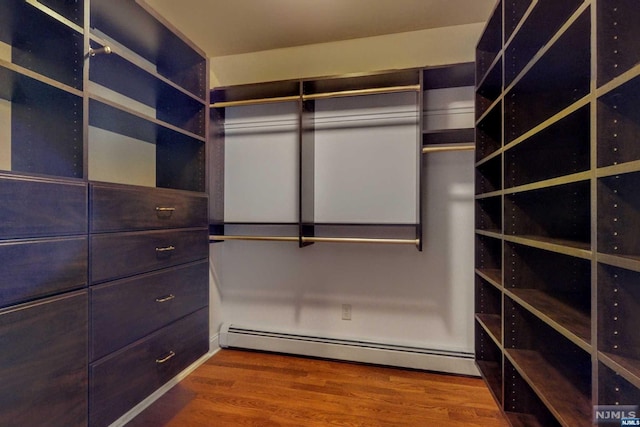 spacious closet featuring hardwood / wood-style floors and a baseboard radiator