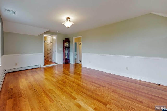 spare room featuring baseboard heating and light hardwood / wood-style flooring