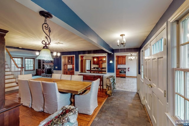 dining area with beamed ceiling, baseboard heating, wooden walls, and a chandelier