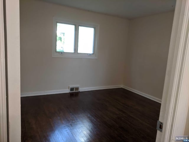 spare room featuring dark wood-type flooring