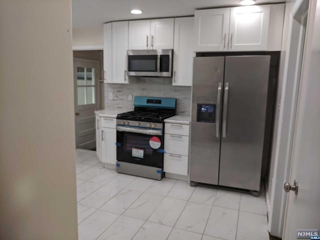 kitchen with white cabinets, decorative backsplash, and stainless steel appliances