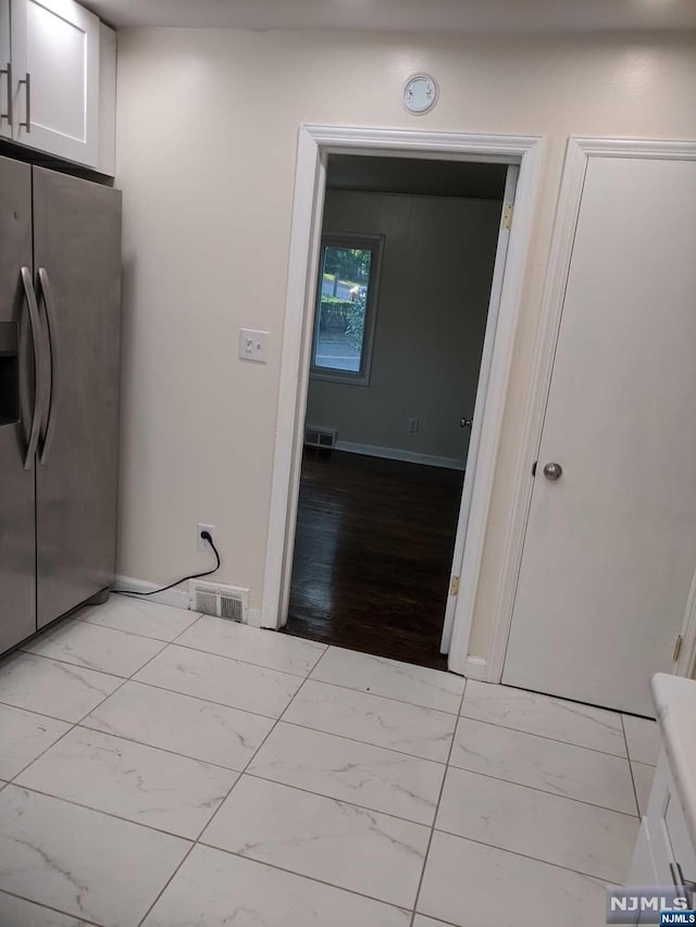 kitchen with light hardwood / wood-style floors, white cabinetry, and stainless steel refrigerator with ice dispenser