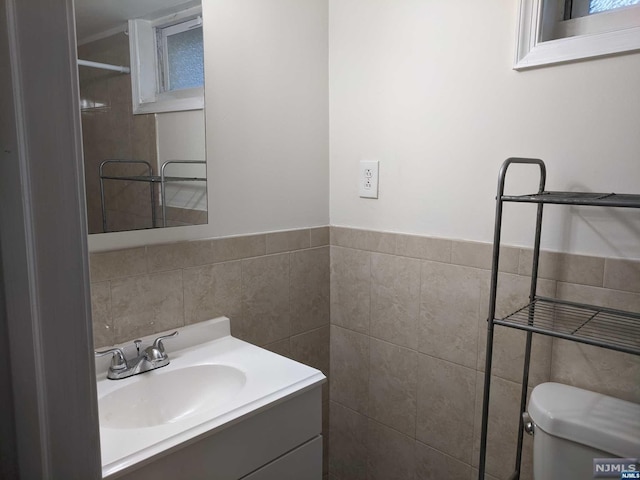 bathroom featuring vanity, toilet, and tile walls