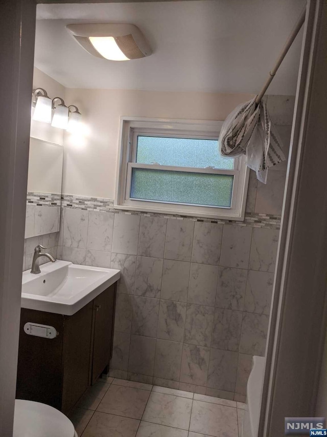 bathroom featuring tile patterned floors, vanity, toilet, and tile walls