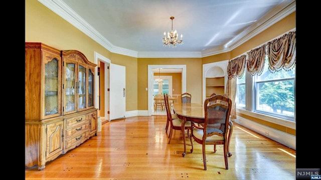 dining space featuring light wood-type flooring, ornamental molding, and a chandelier