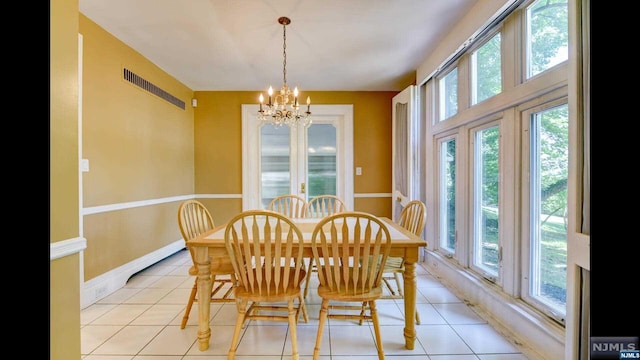 dining space featuring light tile patterned flooring, a healthy amount of sunlight, and a notable chandelier