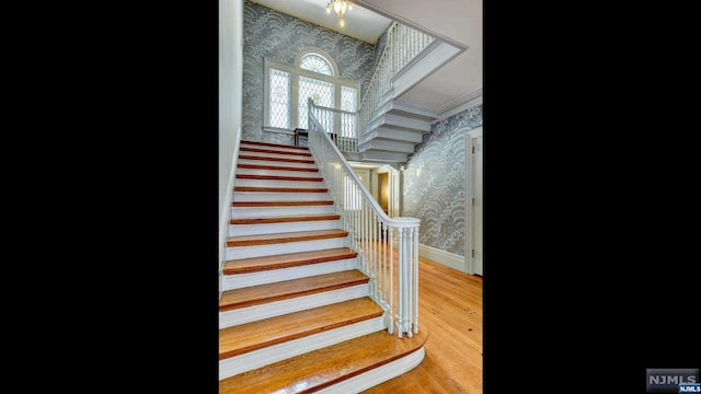 stairway with wood-type flooring and crown molding