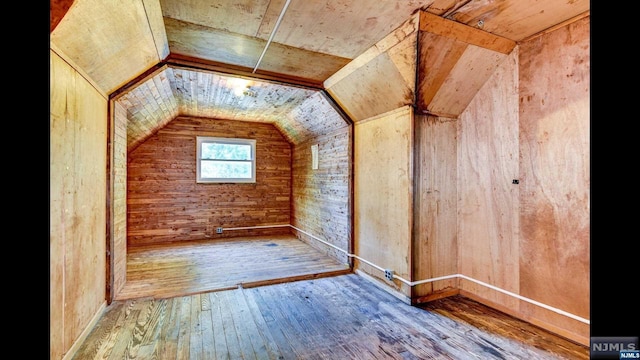 bonus room featuring hardwood / wood-style flooring, lofted ceiling, and wood walls