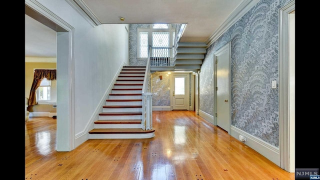 stairway with hardwood / wood-style floors, plenty of natural light, and crown molding