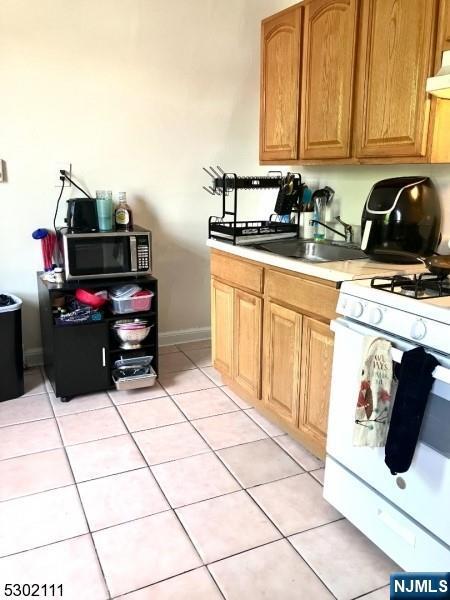 kitchen featuring light tile patterned floors, white range with gas cooktop, and sink