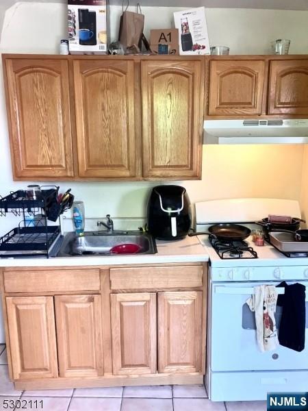 kitchen featuring light tile patterned floors, sink, and white gas stove