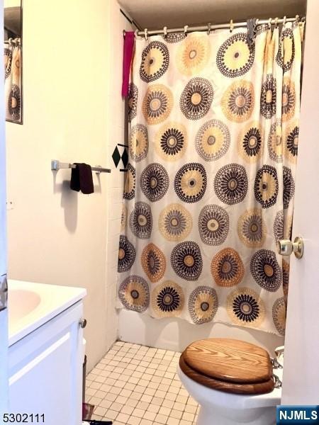 bathroom with toilet, vanity, and tile patterned floors