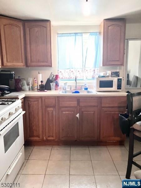 kitchen featuring light tile patterned flooring, sink, and white appliances