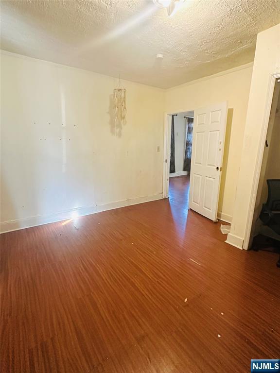 empty room with dark wood-type flooring and a textured ceiling