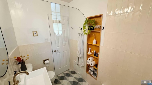 bathroom featuring tile patterned flooring, toilet, and tile walls