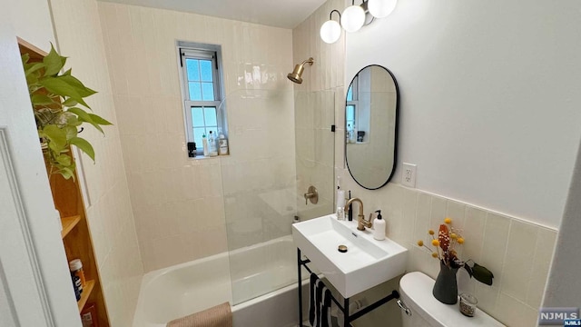 full bathroom featuring sink, toilet, tile walls, and tiled shower / bath