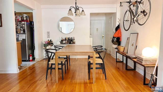 dining area with light hardwood / wood-style floors and an inviting chandelier