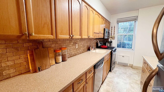 kitchen featuring light stone countertops, decorative backsplash, sink, and stainless steel appliances