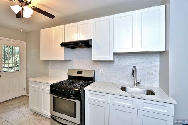 kitchen featuring stainless steel gas range oven, white cabinetry, sink, and light stone counters