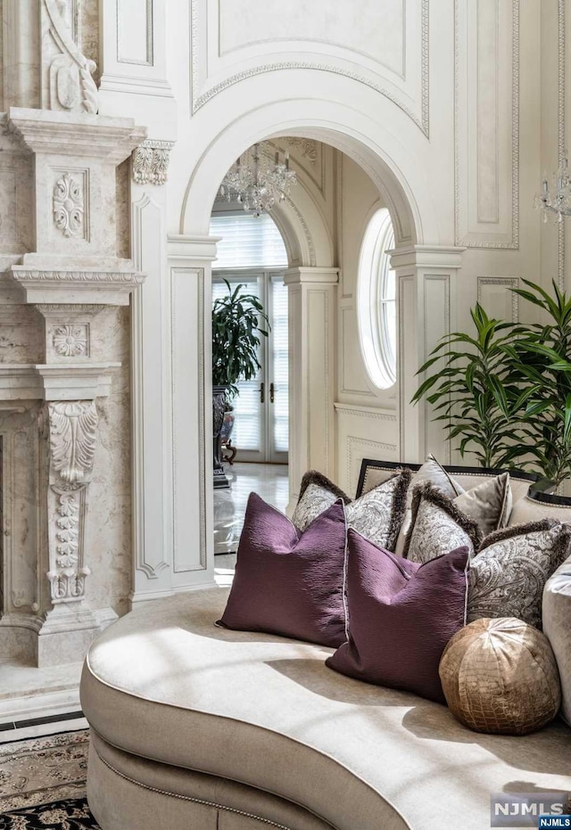 living area with a high ceiling, decorative columns, and an inviting chandelier