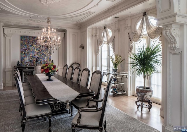 dining room featuring hardwood / wood-style flooring, a notable chandelier, a healthy amount of sunlight, and crown molding