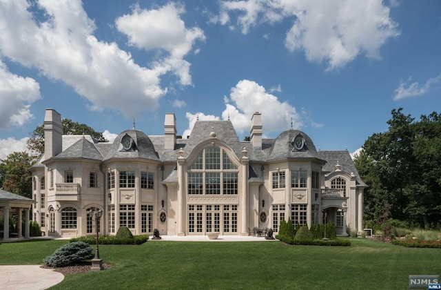 rear view of property featuring a yard, french doors, and a balcony