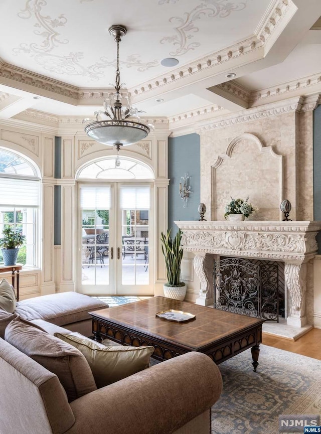 living room featuring coffered ceiling, french doors, a premium fireplace, light wood-type flooring, and ornamental molding