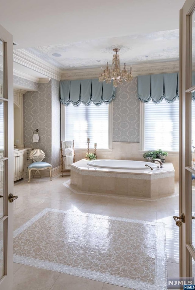 bathroom featuring an inviting chandelier, ornamental molding, and tiled tub