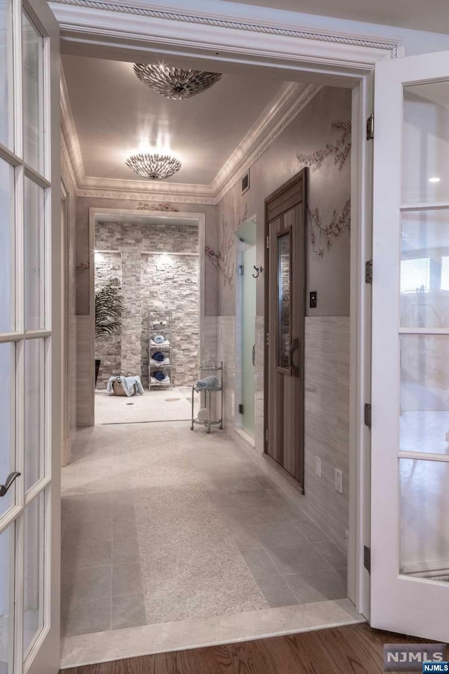 hall featuring wood-type flooring, tile walls, and ornamental molding