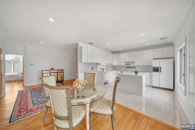 dining space featuring light wood-type flooring and crown molding