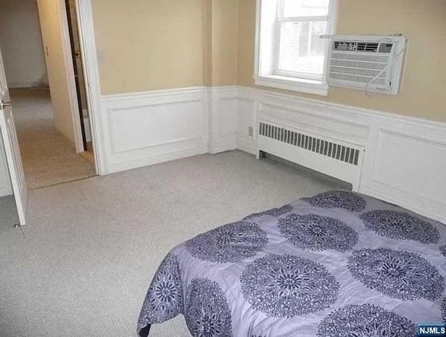 bedroom with light colored carpet, radiator heating unit, and a wall mounted AC