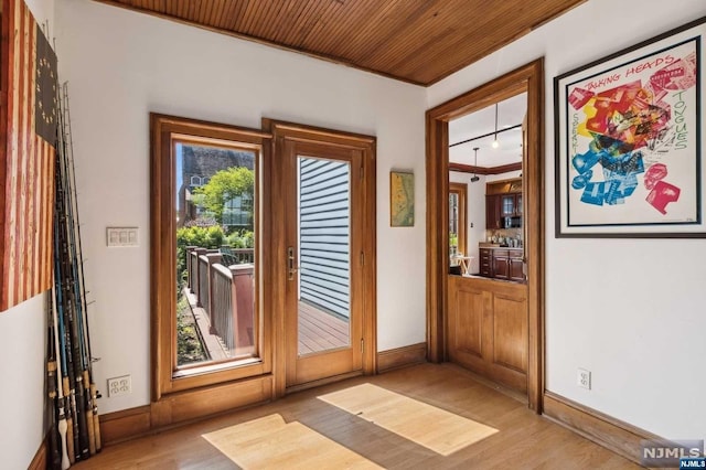 doorway with light hardwood / wood-style flooring, wood ceiling, and ornamental molding