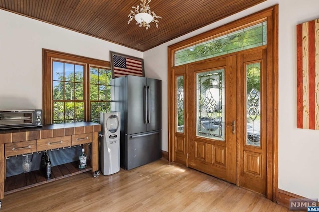 interior space featuring a chandelier, ornamental molding, light wood-type flooring, and wooden ceiling