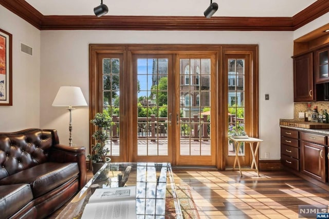 doorway to outside featuring hardwood / wood-style flooring and crown molding