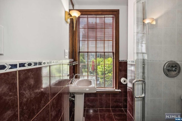 bathroom with sink, tile patterned flooring, an enclosed shower, and tile walls