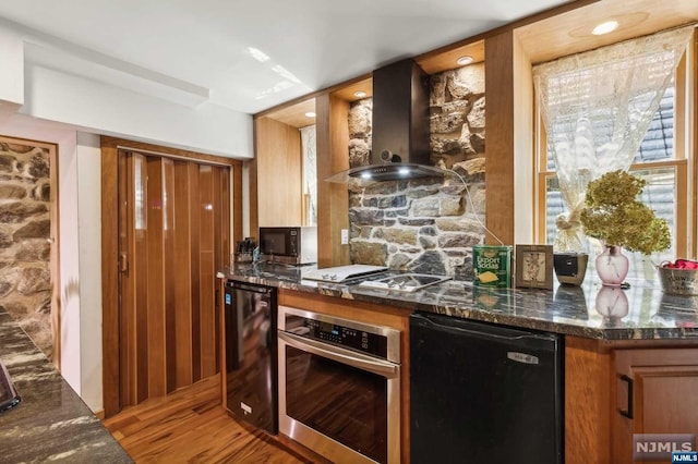 kitchen with wall chimney exhaust hood, beverage cooler, stainless steel appliances, dark stone counters, and wood-type flooring