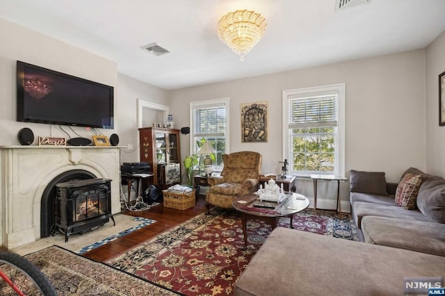 living room featuring a wood stove, a chandelier, and wood-type flooring