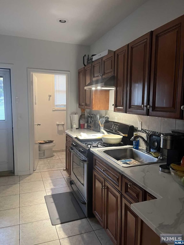 kitchen with plenty of natural light, stainless steel stove, light tile patterned floors, and sink