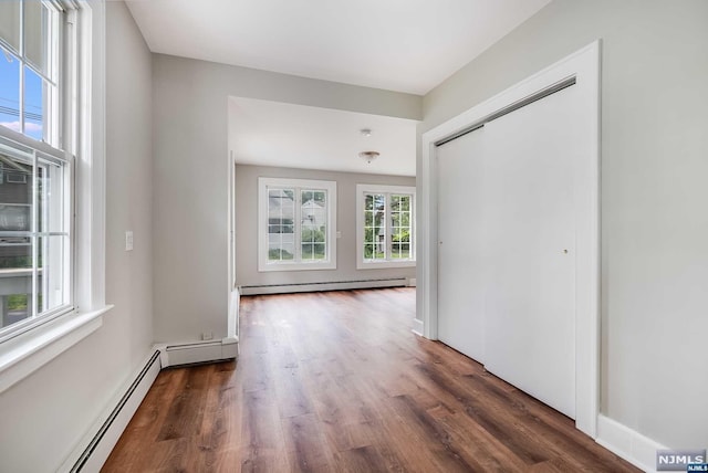 interior space with a healthy amount of sunlight, dark hardwood / wood-style flooring, and baseboard heating