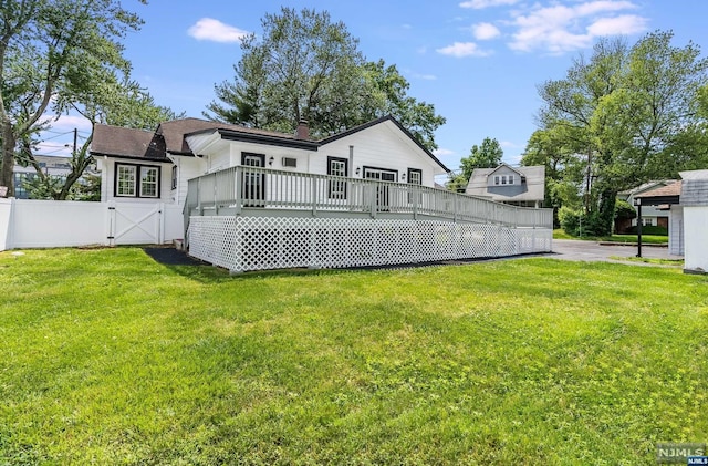 rear view of property featuring a wooden deck and a yard