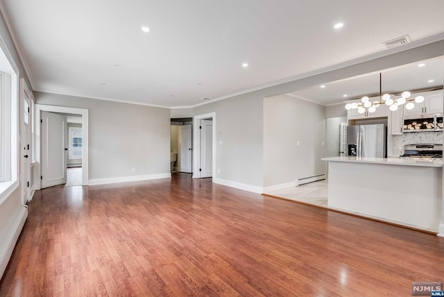 unfurnished living room with light wood-type flooring, an inviting chandelier, baseboard heating, and crown molding