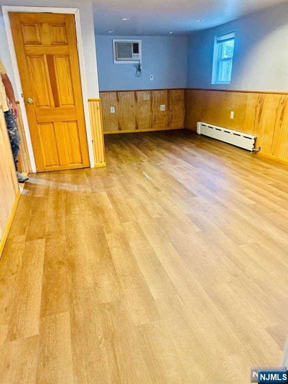 821 Roosevelt Ave, Secaucus, NJ 07094 - empty room featuring wooden walls, a wall mounted air conditioner, baseboard heating, and light hardwood / wood-style flooring