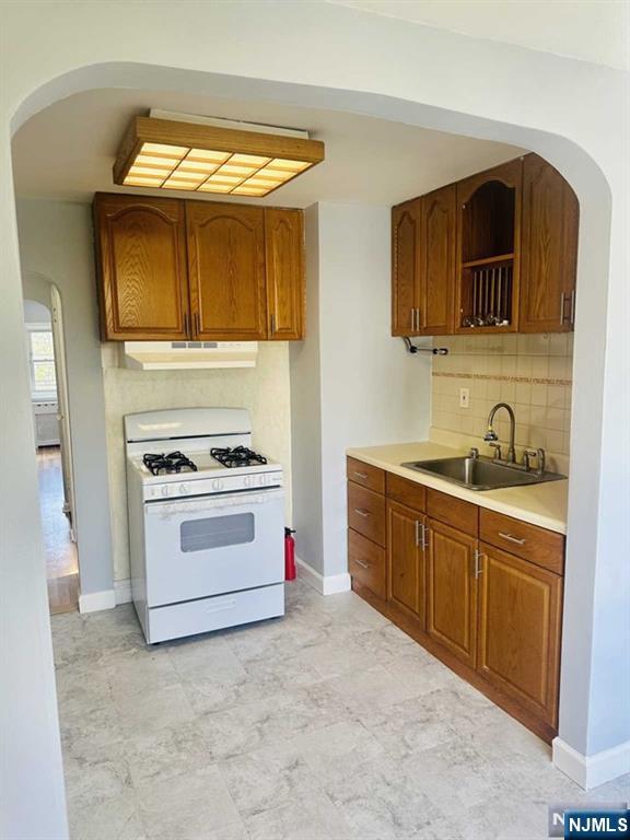 821 Roosevelt Ave, Secaucus, NJ 07094 - kitchen with sink, backsplash, and white gas stove