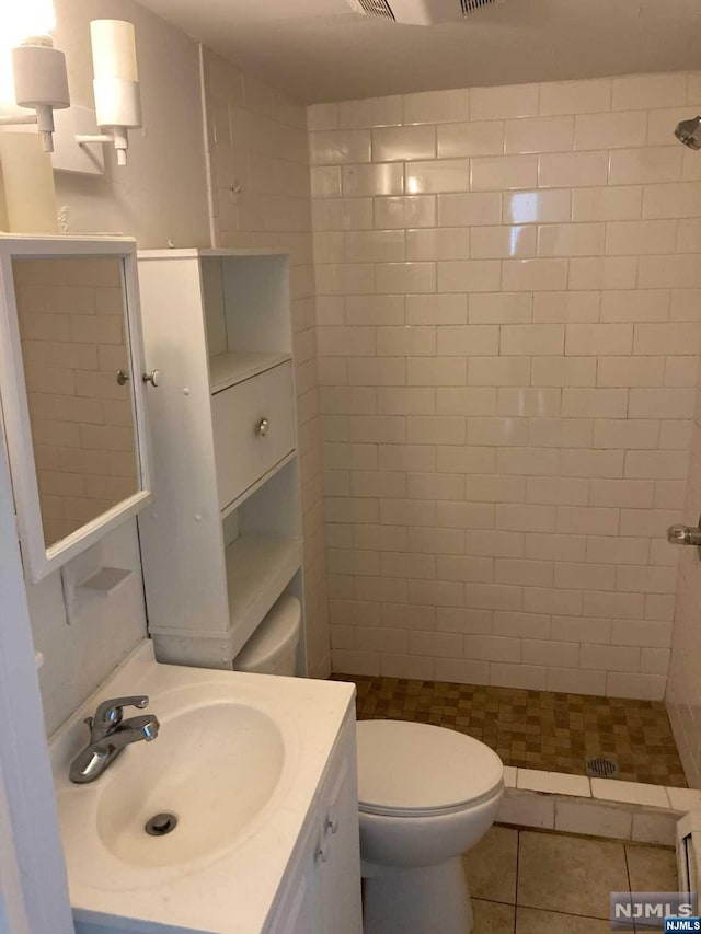 bathroom featuring tiled shower, tile patterned floors, and toilet