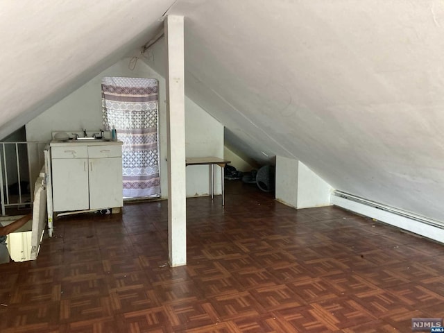 additional living space featuring dark parquet floors, lofted ceiling, and baseboard heating