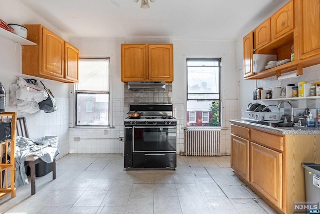 kitchen with a wealth of natural light, black gas stove, tile walls, and radiator